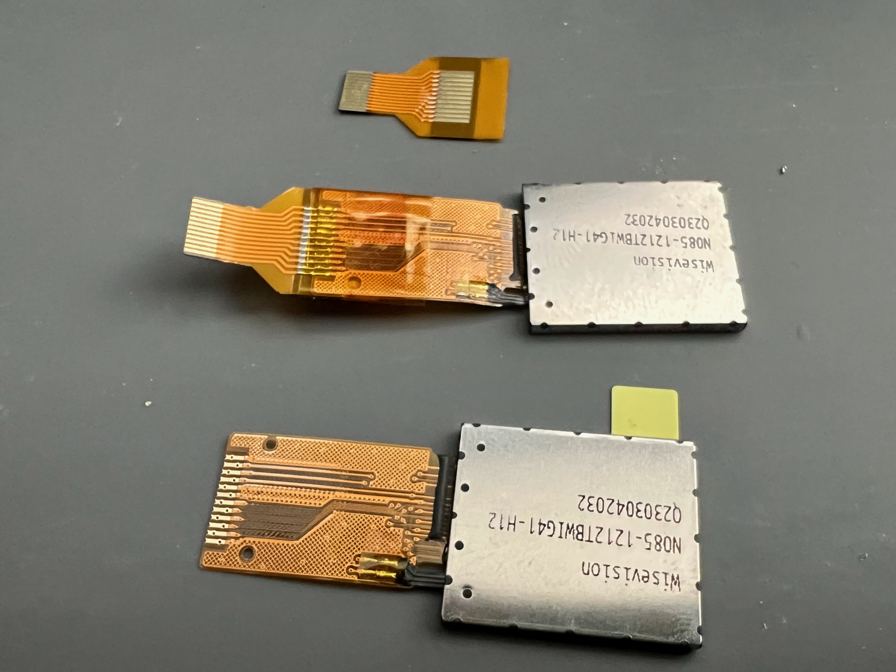 Top: flat flex extension cable for the LCDs; middle: FFC extension soldered onto a LCD's cable; bottom: LCD flipped over showing FFC pads to solder onto